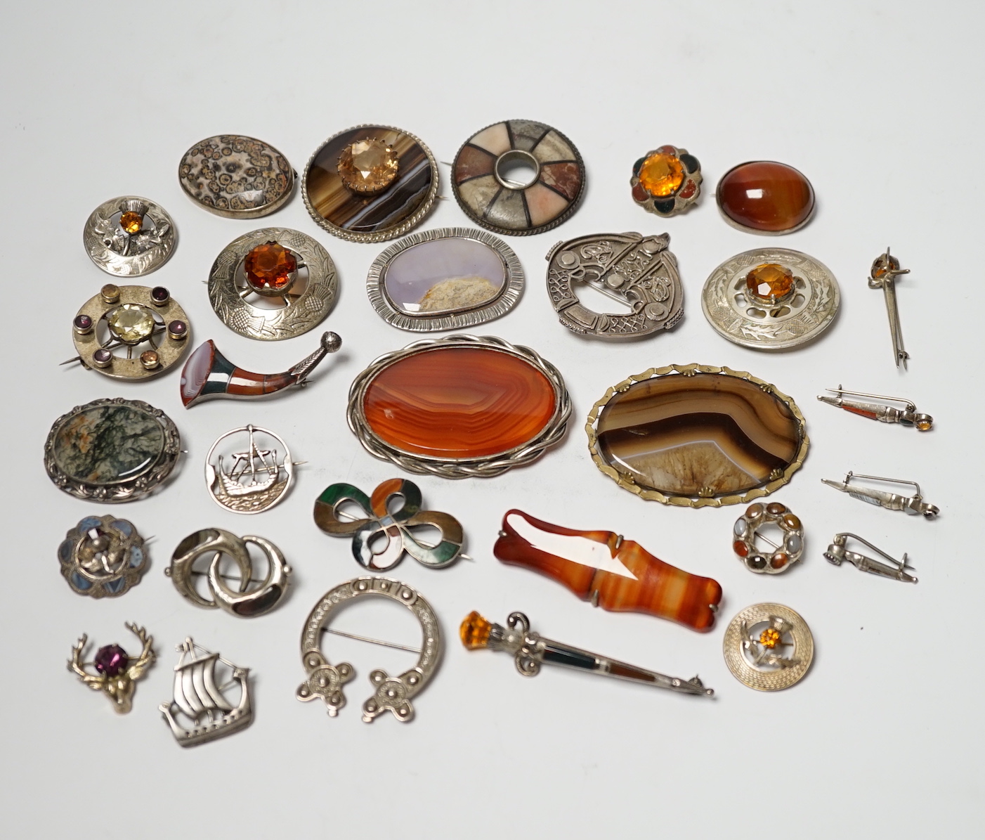 A small collection of mainly silver, sterling and white metal jewellery including Celtic brooches, Iona ship brooch, a Scottish hardstone set bugle brooch and other moss agate set and banded agate set items, largest broo